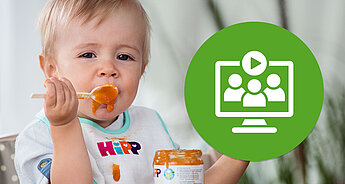 Ein Baby isst einen Löffel mit orangefarbenem Essen. Auf der rechten Seite ist ein grünes, kreisförmiges Symbol zu sehen, das einen Computerbildschirm mit drei Silhouetten darstellt.