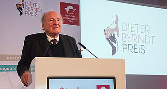 Ein älterer Mann spricht auf einem Podium vor einem Hintergrund, der das Logo des Dieter Berndt Preises und den Text des Deutschen Verpackungspreises zeigt.