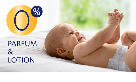 Ein Baby, das auf einem Bett liegt und sich an den Händen festhält, vor dem Hintergrund eines hellen Zimmers.