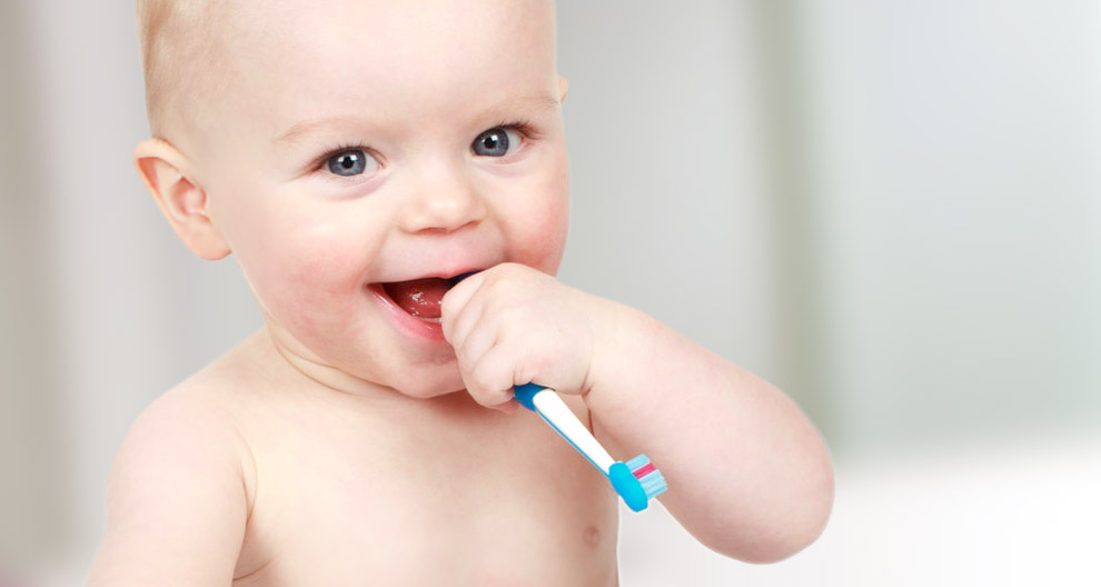 Ein Baby mit blauen Augen, das auf einer Zahnbürste kaut.